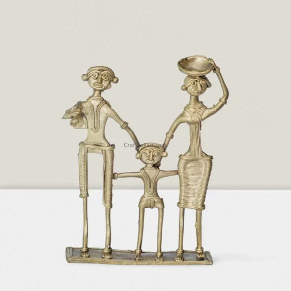 A bronze Dokra sculpture of a family with a father, mother, and child holding hands. The father is holding an instrument, and the mother balances a bowl on her head.